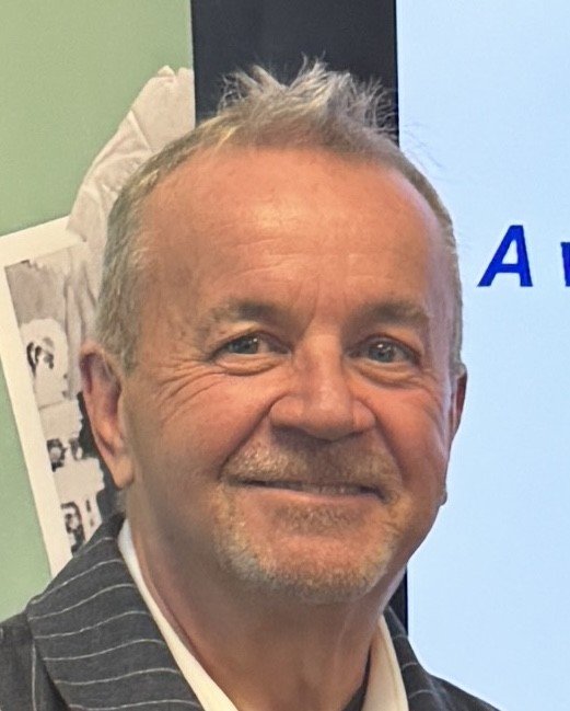 Andy is smiling while looking at the camera.